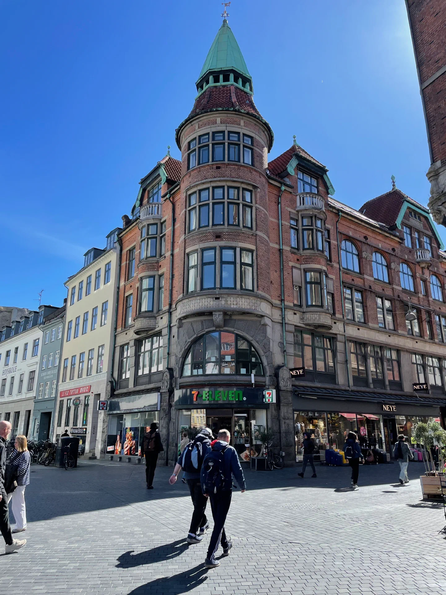 An ornate turreted corner building over a pedestrian shopping street in Copenhagen