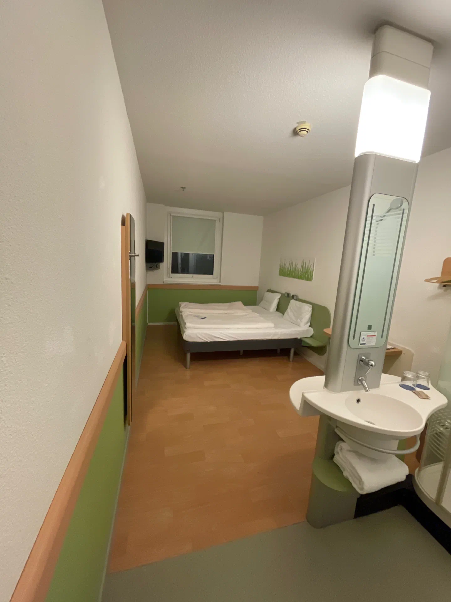 A compact, green-accented budget hotel room in Vienna